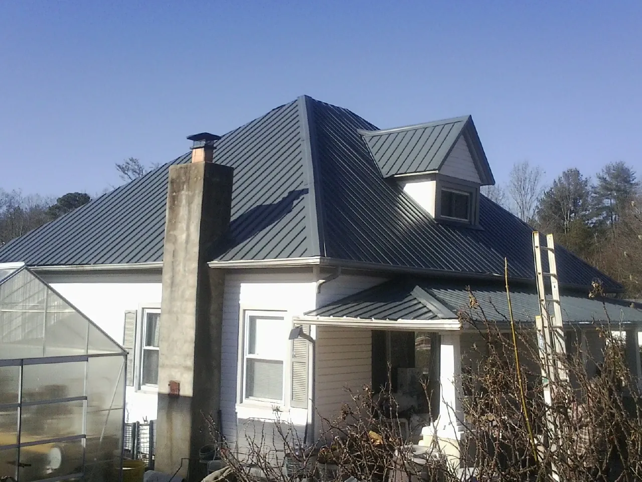 Dark blue standing seam metal roof on a white farmhouse with dormer — Slate & Tile Roof Repair by Roofing Brothers in Gwynedd