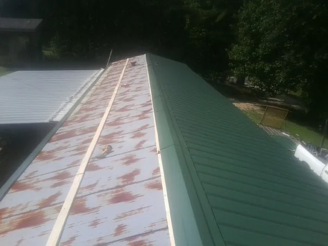 Old rusted panels beside newly installed green metal roofing — Wind Damage Roof Repair by Roofing Brothers in Gwynedd
