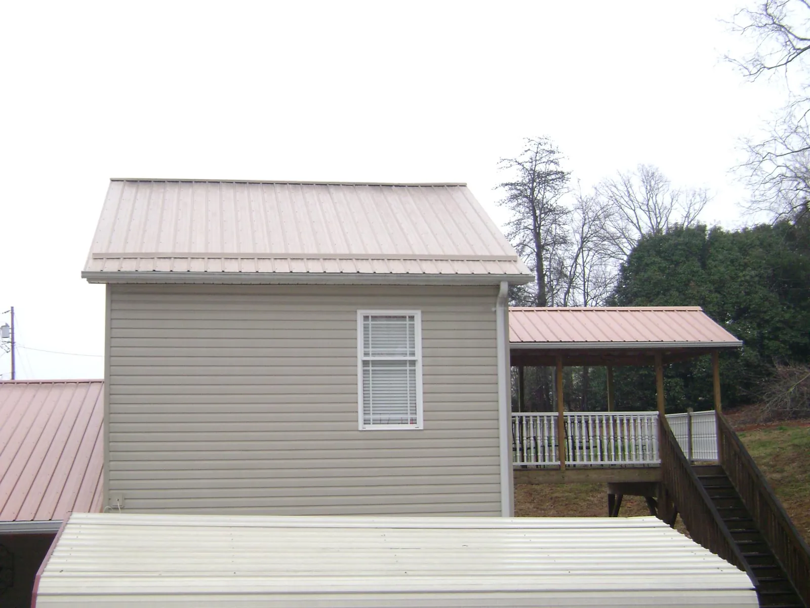Tan metal roofs on a two story addition and attached porch, from a Roof Replacement job in Gwynedd